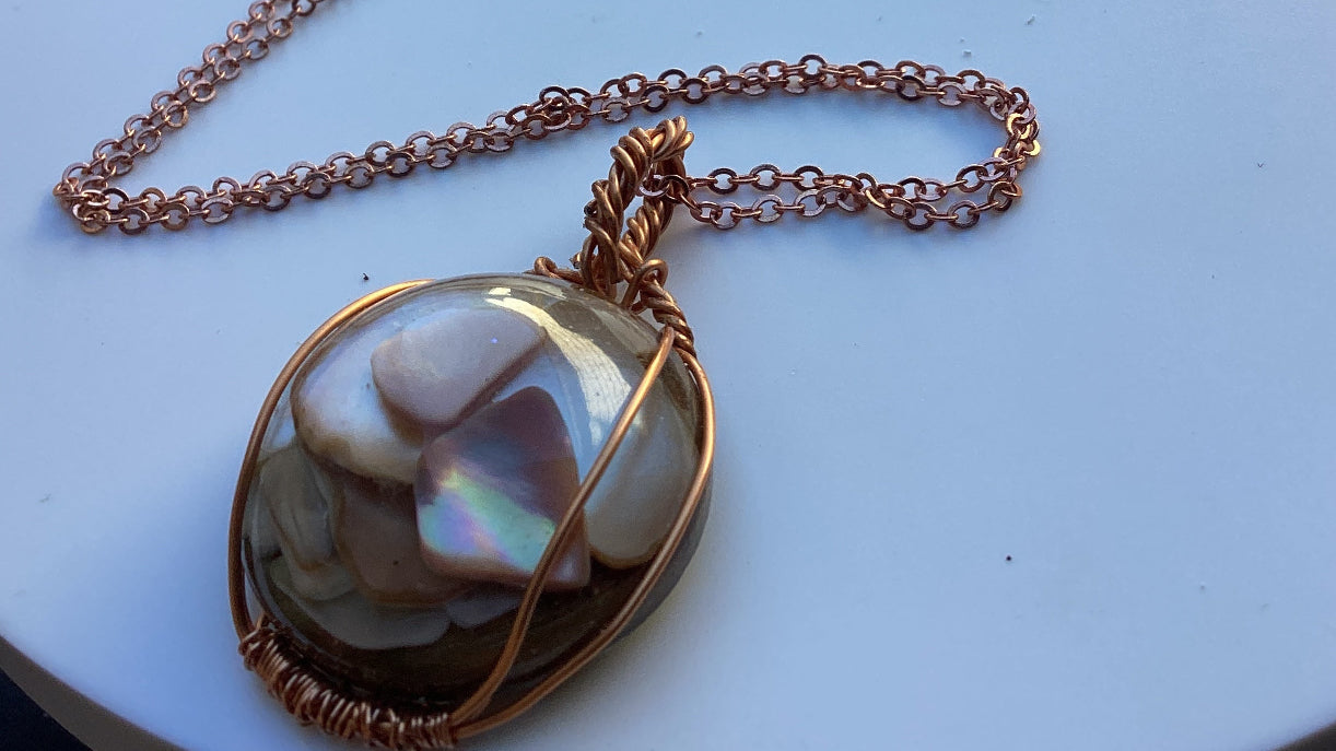 The beautiful wired and chained, necklace has a 1 1/2 in round resin pendant incased with real Mother of pearl chips.  It’s Stunning!